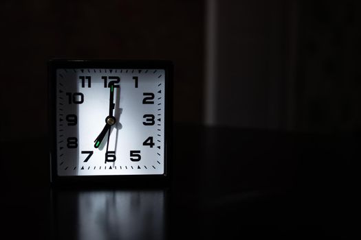 Black clock in morning in shadows closeup, copy space