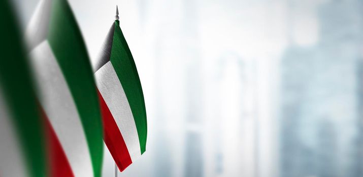 Small flags of Kuwait on a blurry background of the city.