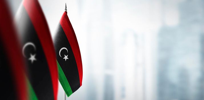 Small flags of Libya on a blurry background of the city.