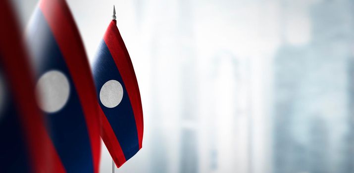 Small flags of Laos on a blurry background of the city.