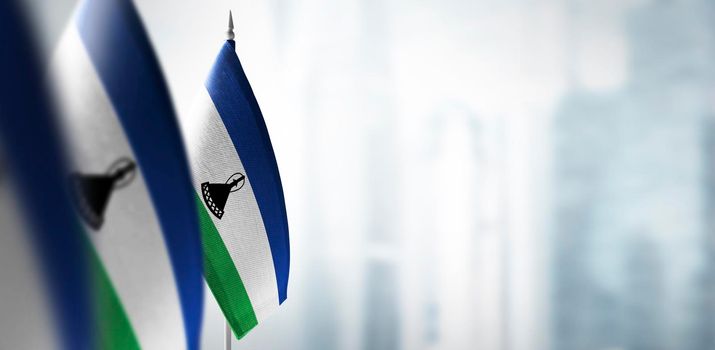 Small flags of Lesotho on a blurry background of the city.