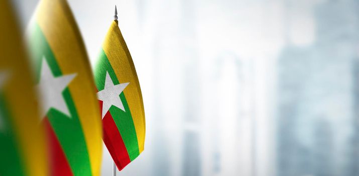 Small flags of Myanmar on a blurry background of the city.