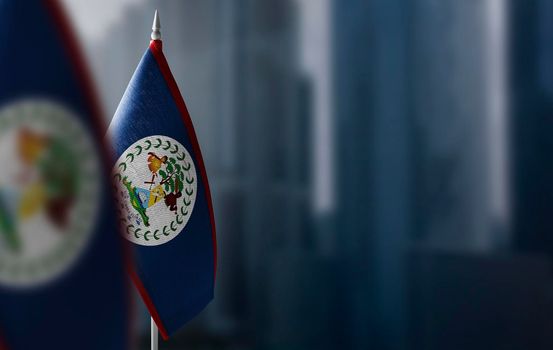 Small flags of Belize on a blurry background of the city.