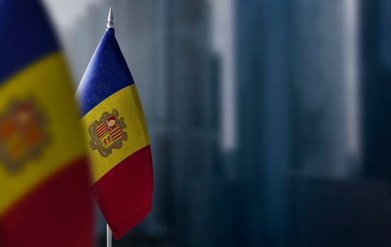 Small flags of Andorra on a blurry background of the city.