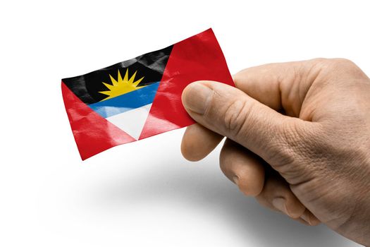 Hand holding a card with a national flag the Antigua and Barbuda.