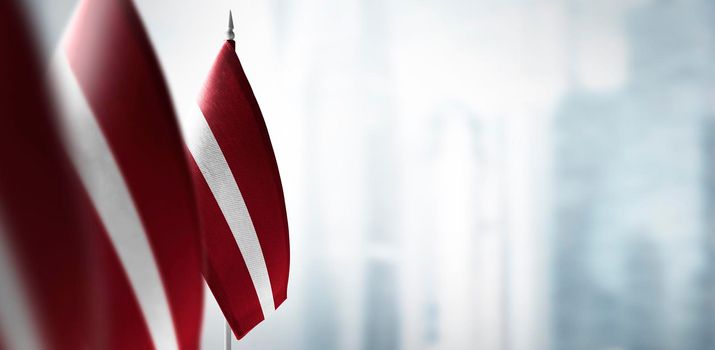 Small flags of Latvia on a blurry background of the city.