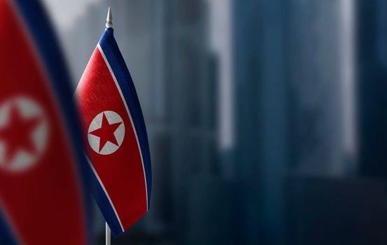 Small flags of North Korea on a blurry background of the city.