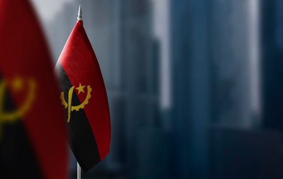 Small flags of Angola on a blurry background of the city.