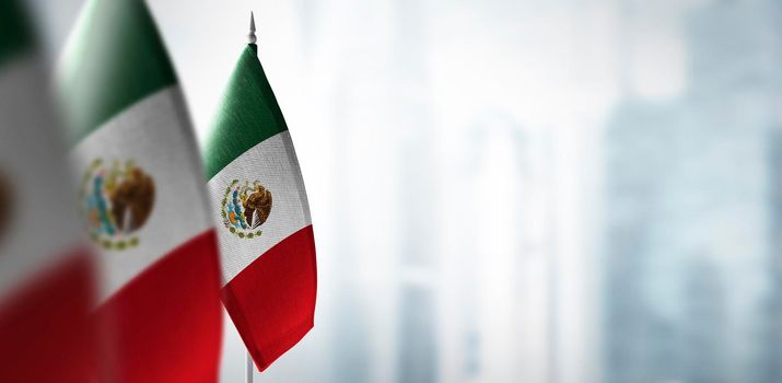 Small flags of Mexico on a blurry background of the city.