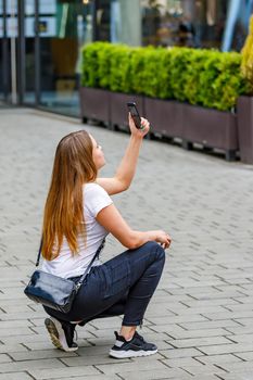 Girl tourist photographs the sights of the city on a mobile phone.