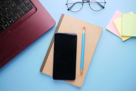 top view of smart phone and notepad on table .