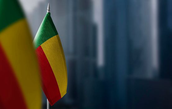 Small flags of Benin on a blurry background of the city.