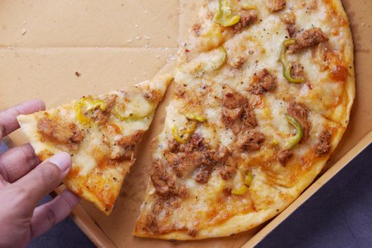 top view of man hand picking slice of pizza from a plate .