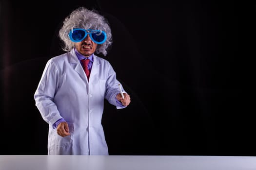 Angry science teacher in white coat with unkempt hair in funny eye glasses holding a wand to point at the blackboard