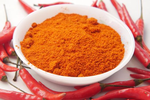 Chili powder and dried peppers on table background.