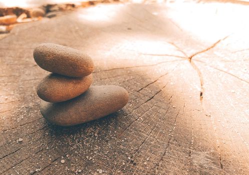 Yoga Zen stones balance on top of each other. Sea pebbles lies on a wooden saw lit by the sun. Copy space.