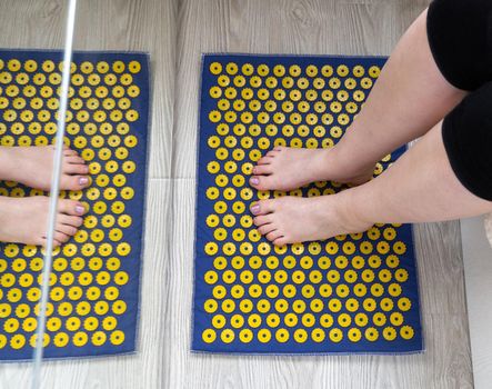 Women's feet stand on a needle mat - foot massage using an applicator Kuznetsov, Russia