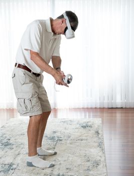 Senior man playing a golf or putting game on a modern virtual reality VR headset in home