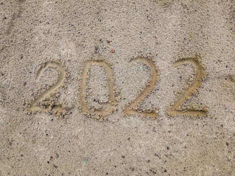 Happy New Year 2022. The symbol of the number 2022 on the sand is a New Year Greeting Card. Copy space.