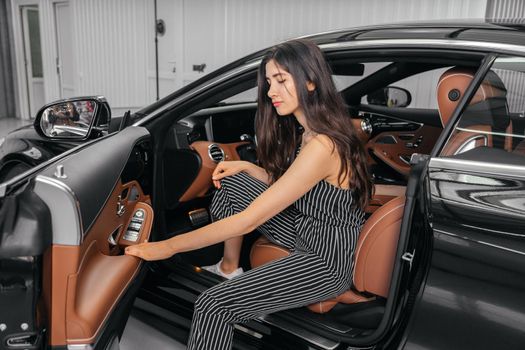 Young asian woman sitting in luxury car in garage before starting engine and driving