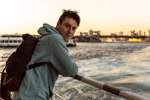 A young travelling man with backpack on a ferry floats acrossing the sea at sunset. The beginning of a great adventure.