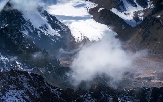 Rocks of the highlands, the road among the snow-capped peaks of the mighty mountains in the sun.