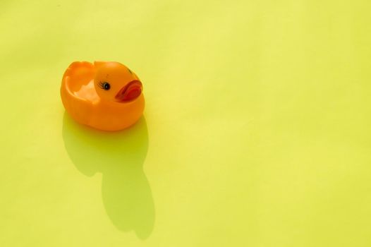 High Angle View Of Pink Rubber Duck On Table. Single pink color rubber duck isolated on light yellow background. Table top view. Copy space for text.