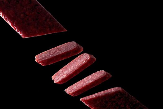 Slice of salami on black background. Flying salami.