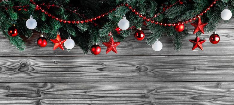 Christmas decoration with fir branches and red and white christmas balls on dark wooden background with copy space