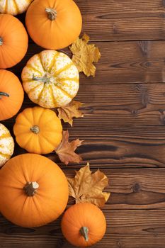 Pumpkins with fall leaves over wooden background. Top view. Frame with copy space for text