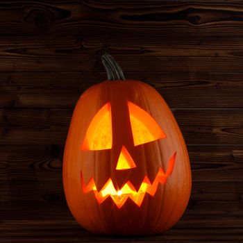 Jack o lantern Halloween pumpkin face on wooden background