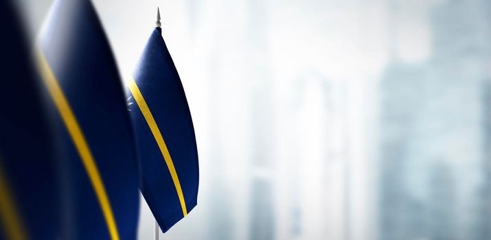 Small flags of Nauru on a blurry background of the city.