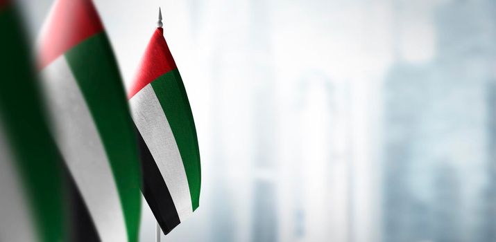 Small flags of United Arab Emirates on a blurry background of the city.