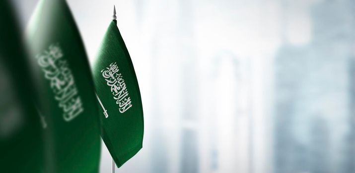 Small flags of Saudi Arabia on a blurry background of the city.