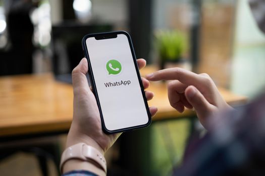 CHIANG MAI, THAILAND - JULY 15 2021 : Man holding a iPhone and open appstore searching social Internet service WhatsApp on the screen. iPhone was created and developed by the Apple inc