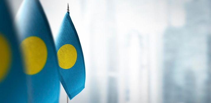 Small flags of Palau on a blurry background of the city.