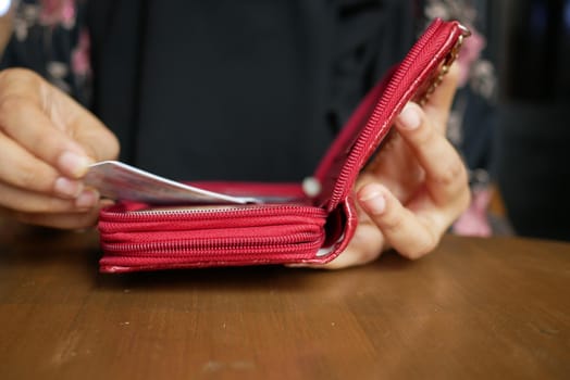 senior women putting card back in her wallet .