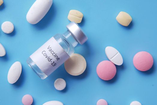 coronavirus vaccine and medical pills on blue ,