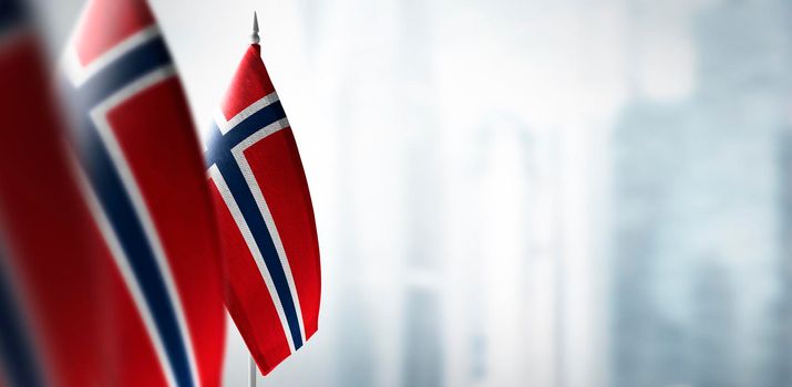 Small flags of Norway on a blurry background of the city.