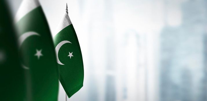 Small flags of Pakistan on a blurry background of the city.