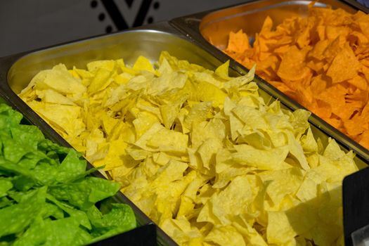 Multi colored tortilla chips in trays on the showcase. Street food festival. Selective focus.