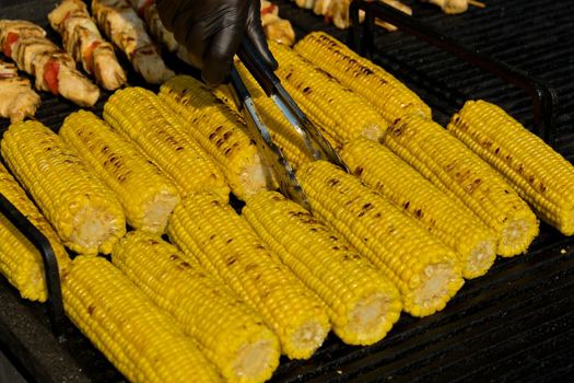 Grilling corn cob. Street food festival. Selective focus.