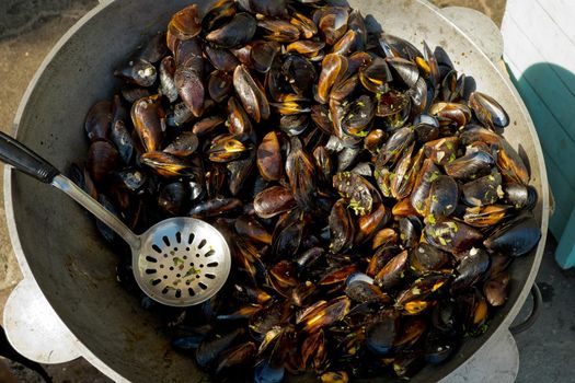 The process of preparing mussels in a large saucepan. Street food festival. Selective focus.