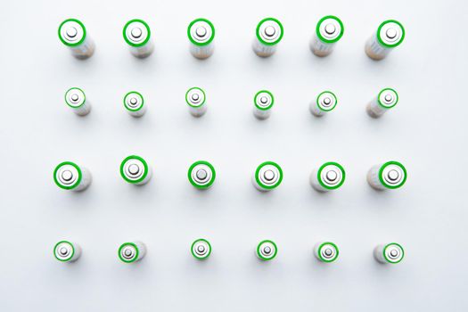 The batteries stand in a row at a distance from each other, alternating rows of large and small batteries on a white background. top view, flat lay, copy space, isolate. High quality photo