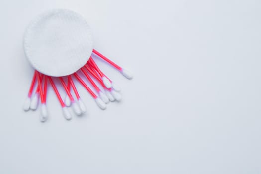 Disposable ear sticks with a red wand and white disposable cotton sponges lie on a white background.. top view, flat lay, copy space, isolate. High quality photo