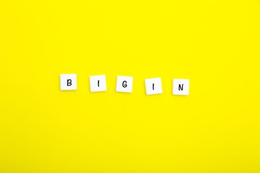 The word BEGIN is written in letters on small white squares on a yellow background. High quality photo
