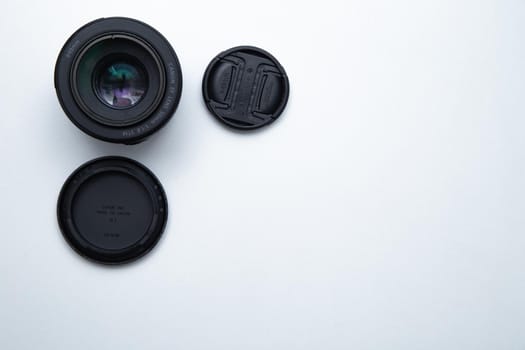 A small fixed lens for a professional camera on a white background with two covers. High quality photo