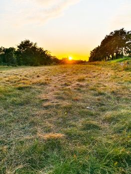 Beautiful sunset over small glade full of cutted grass