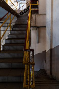 Stairs to up and down with yellow railings seen from mezzanine