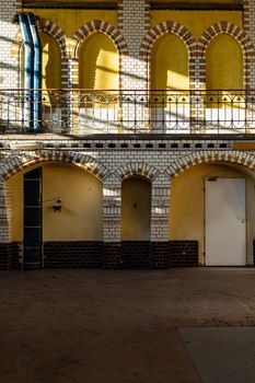 Yellow wall full of arcs made of red and white tiles and balcony inside pumping station